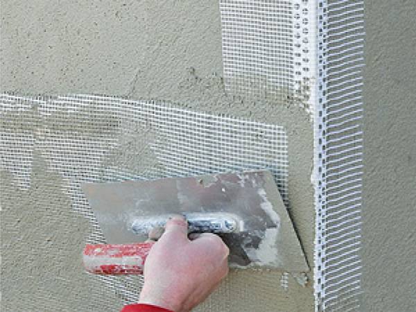 A man is plastering the external wall corner with PVC corner beads.